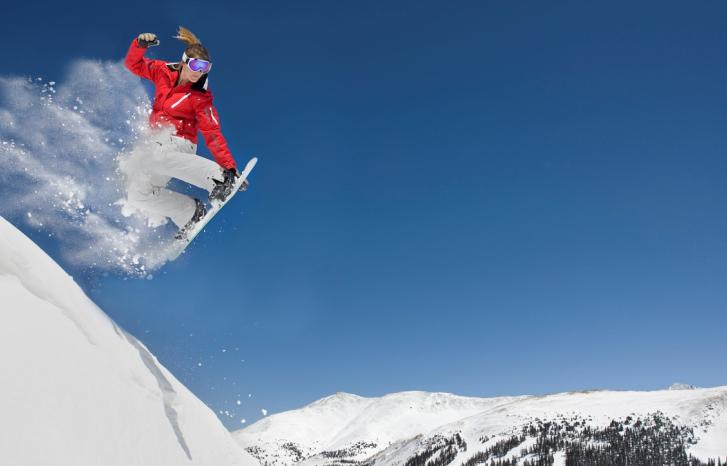 Jente kjører snowboard på fjelltopp