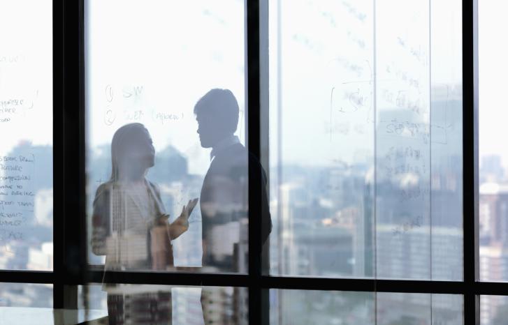 To personer i samtale bak en glassvegg
