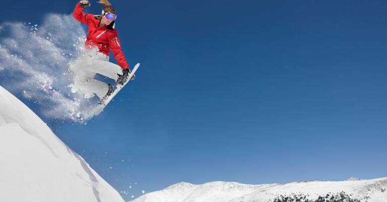 Jente kjører snowboard på fjelltopp
