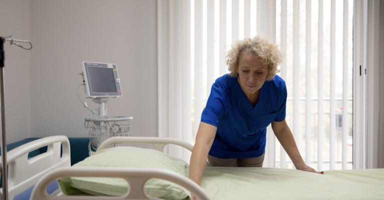 Voksen kvinne rer opp sykehusseng