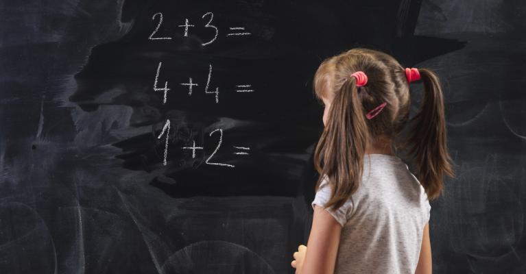 Skolejente med musefletter skriver tall på en tavle