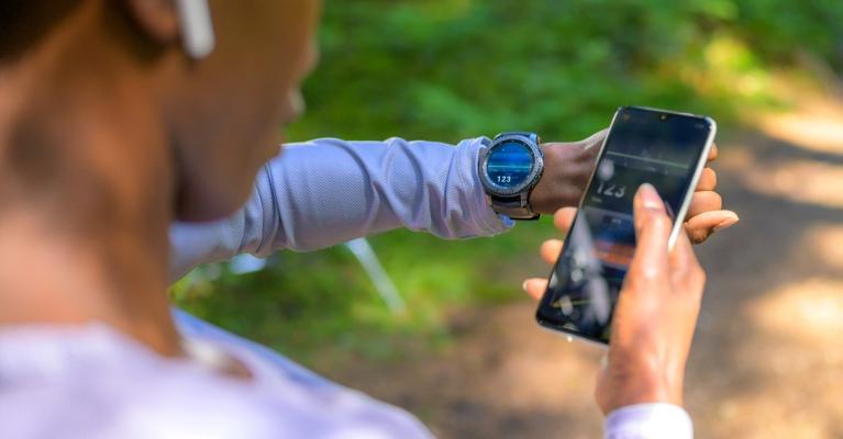 Kvinne som trener sjekker pulsklokke og mobil