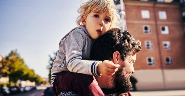 Gutt sitter på skuldrene til mann