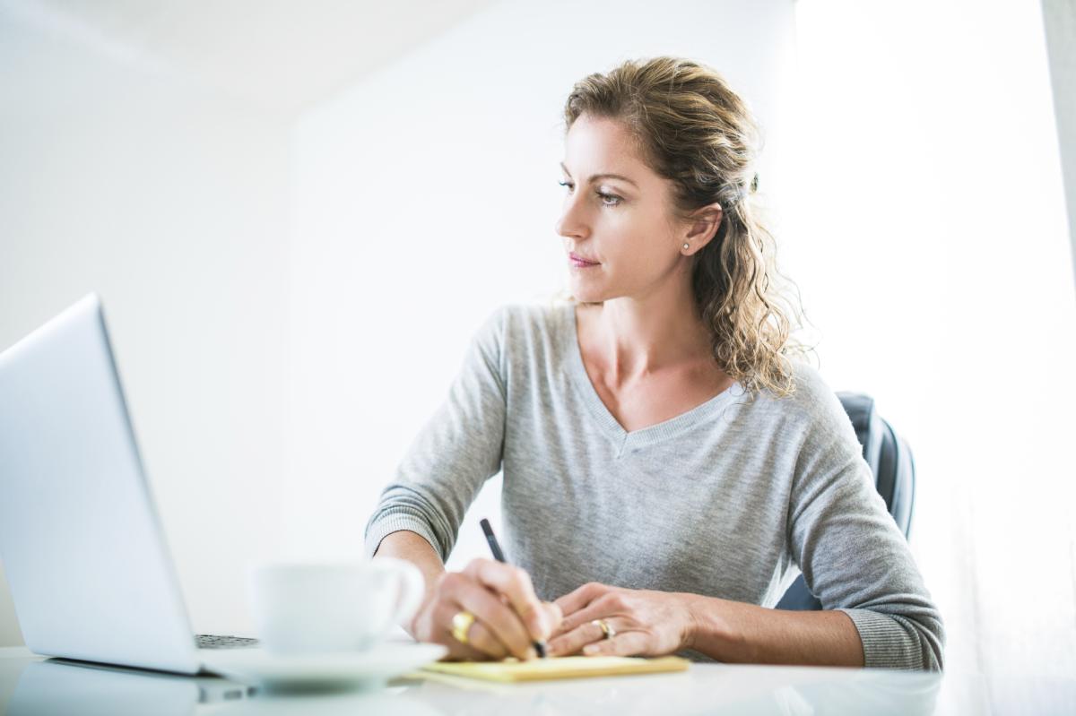 Kvinne skriver og ser på laptop