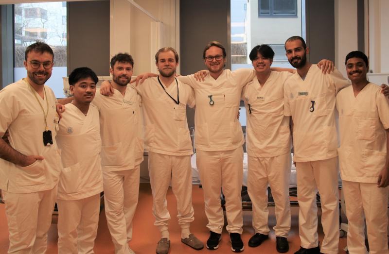 En mannlig høyskolelektor og sju unge menn som studerer til sykepleie ved OsloMet, kledd i hvite uniformer.