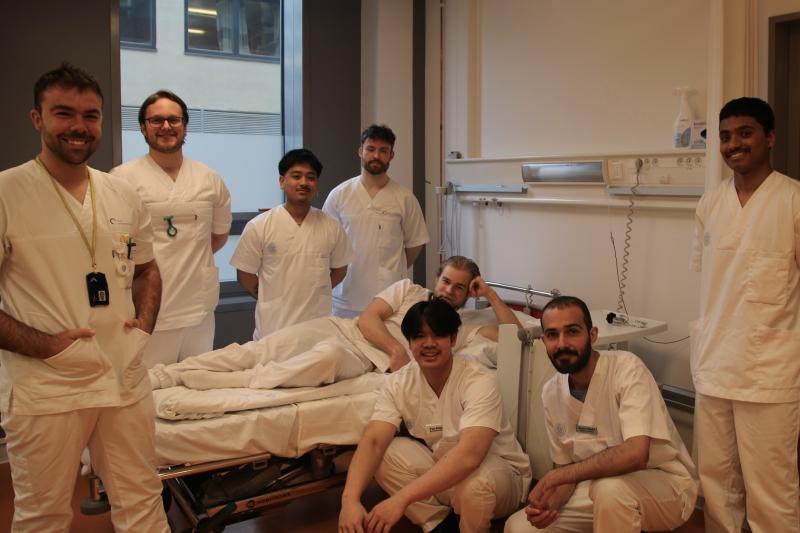 Mannlig høyskolelærer og sju mannlige studenter i uniform fra sykepleieutdanningen ved OsloMet