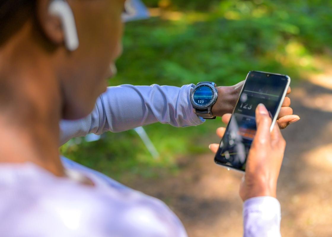 Kvinne som trener sjekker pulsklokke og mobil