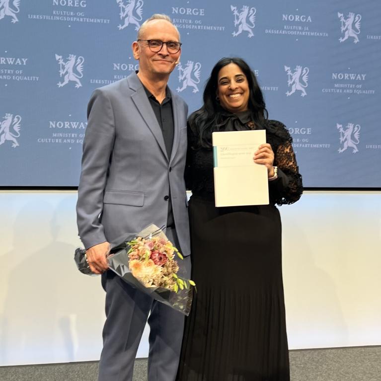 Leder av mannsutvalget Claus Jervell, gir rapporten til statsråd Lubna Jaffery
