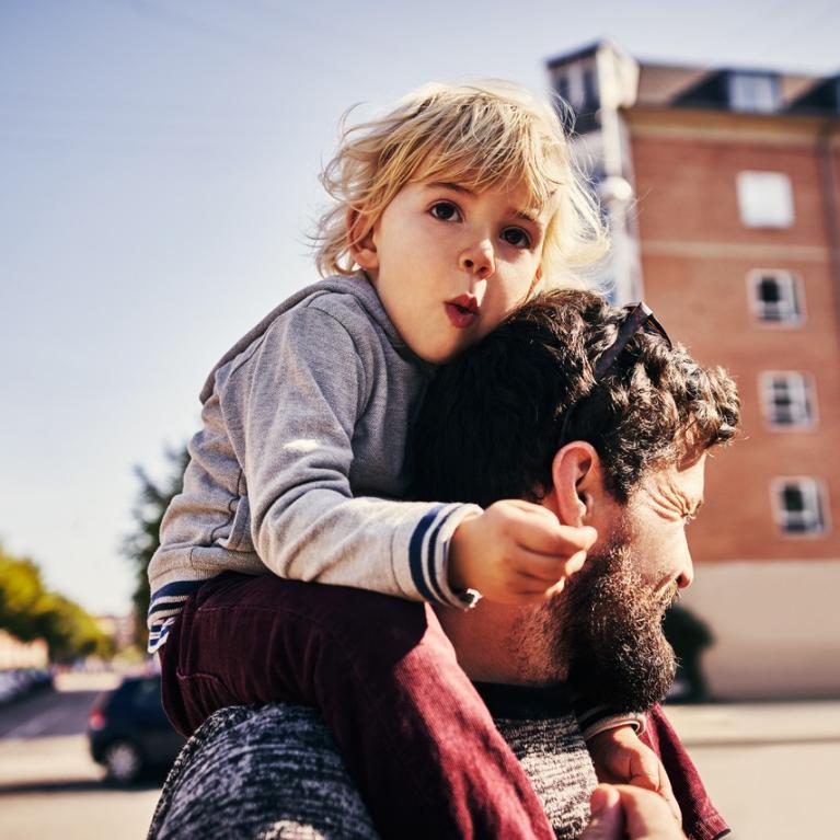 Gutt sitter på skuldrene til mann